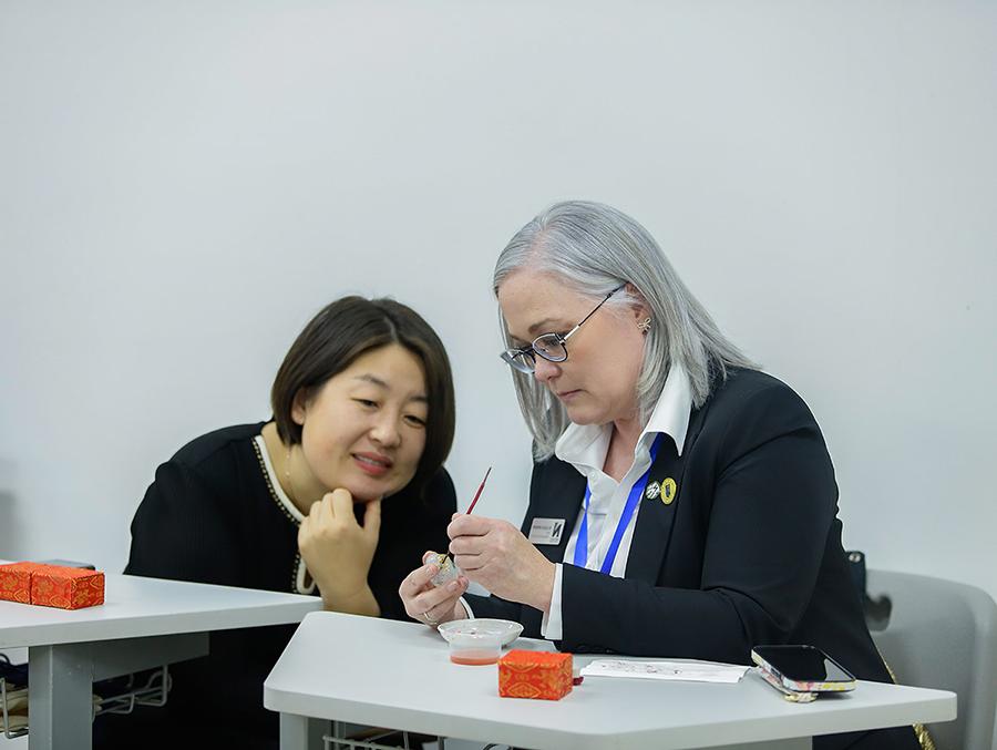 Dr. Elise Hepworth practiced the Chinese art of bottle painting with a delegate of Hebei Normal University. (Photo courtesy of Dr. Shelby Lee/GCBEI)